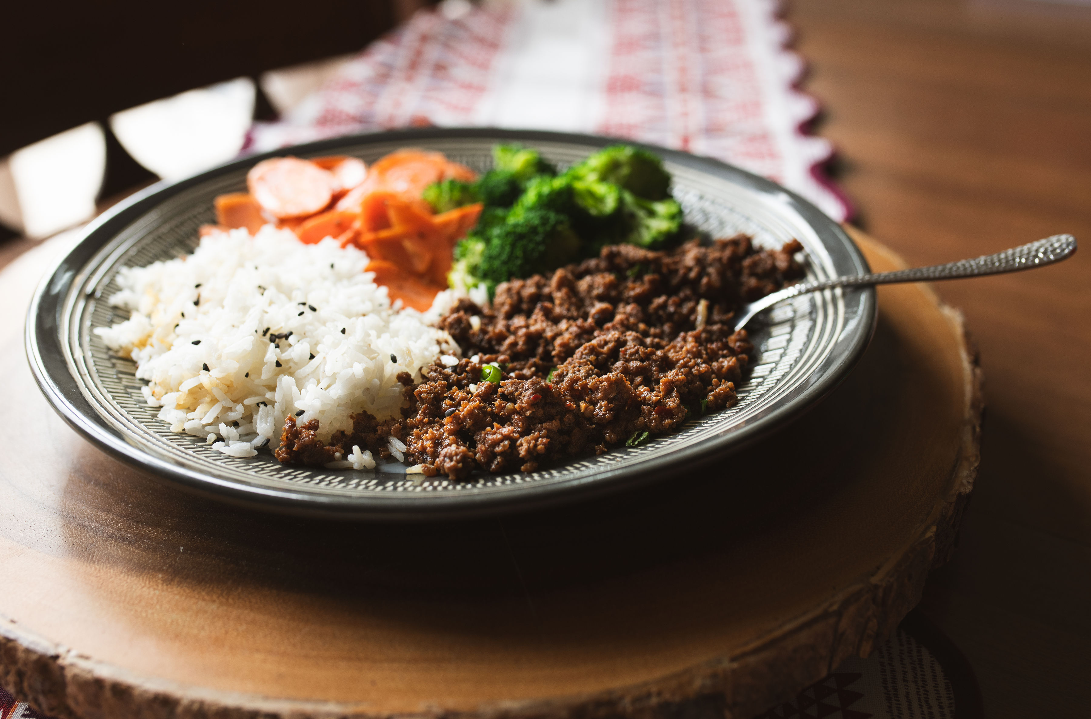 Korean beef bowl with ground beef in savory-sweet sauce, green onions and sesame seeds over jasmine rice with broccoli and carrots